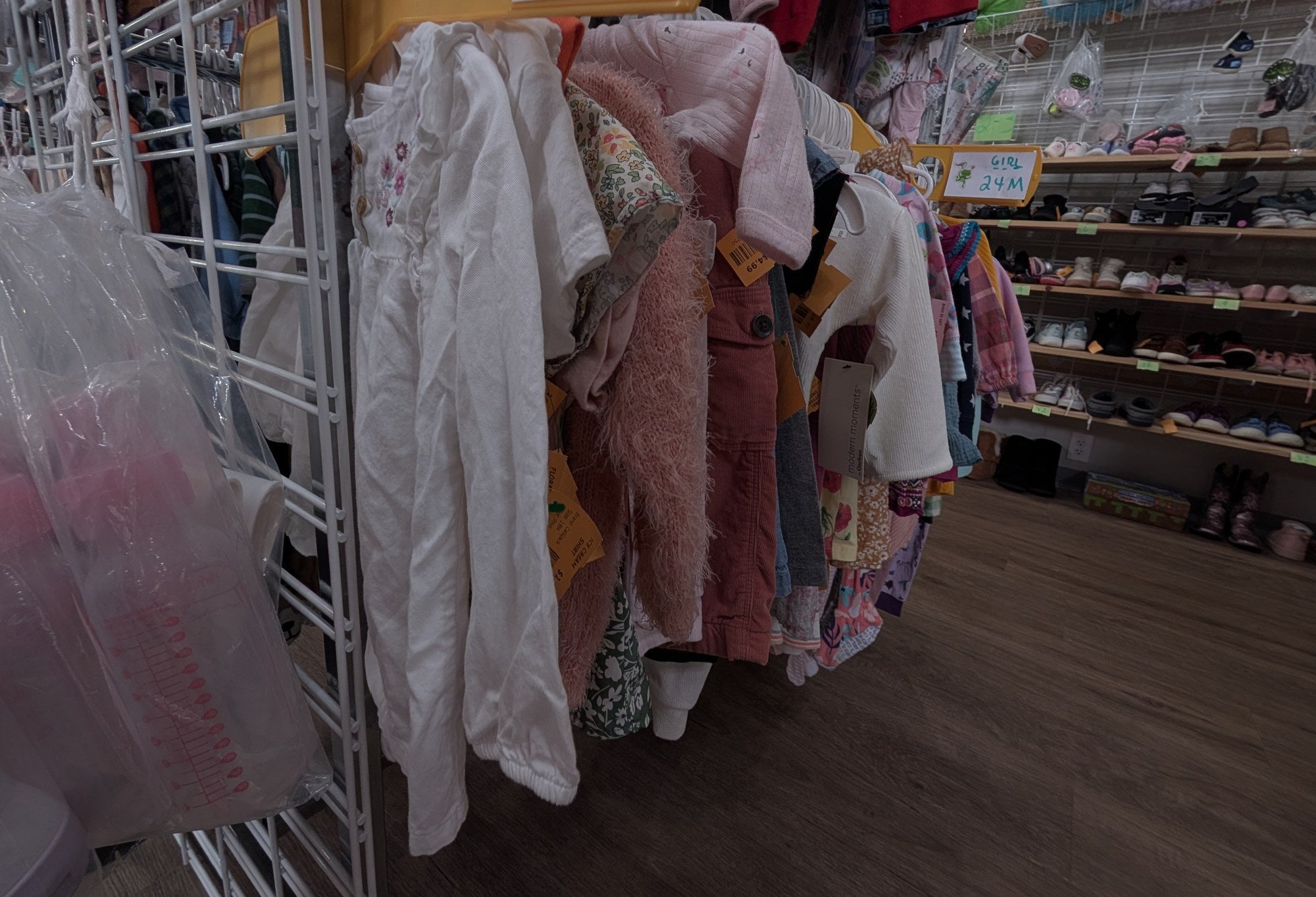 Racks of gently used children’s clothing beside shelves of kids’ shoes at Leapin’ Littles in Historic Downtown Denison, TX