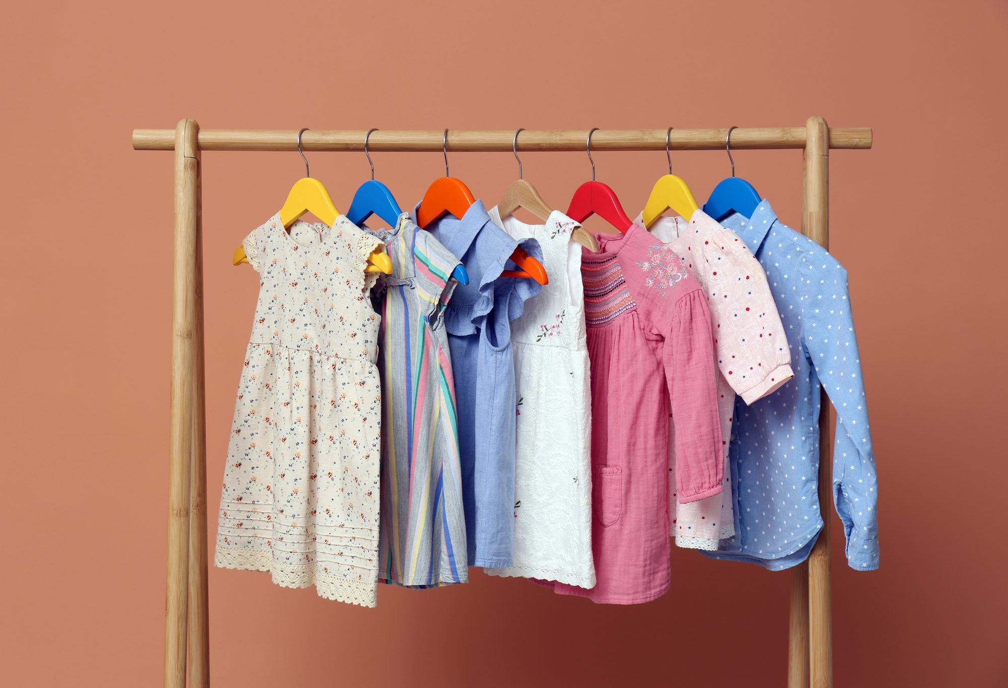 Children's clothing on wooden hangers on a clothing rack